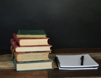 pile of books beside white printer paper and black ballpoint pen