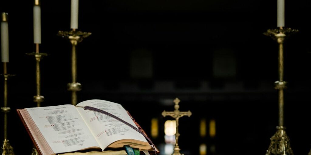 opened book near gold-colored crucifix